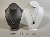 Two necklaces displayed on busts with three pairs of earrings arranged in front, showing the general lot contents and condition.