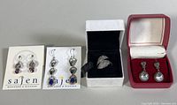Overview photo of all three pairs of earrings and Pandora Angel Wings ring in respective boxes, displayed on gray background.