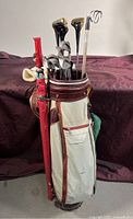 Full view of Constanti golf bag with attached red umbrella and multiple golf clubs inside, showing overall wear and condition.
