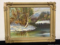 Front view of a framed oil painting by Hazel Mackay showing a winter river landscape scene in a gold frame with corner embellishments.