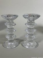 Front view of the pair of clear textured glass candleholders showing the vertically stacked ring design and wide round base.
