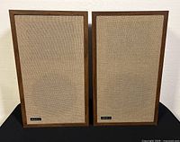 Front view of the pair of Advent stereo speakers showing wooden frames and beige grill cloth.