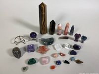 Full layout of all gemstone carvings including obelisks, skull, and various shaped and polished stones on a white surface
