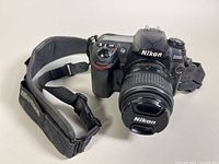 Front and angled view of Nikon D200 camera with neck strap, lens cap attached