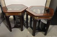 Pair of hexagonal wooden side tables with beveled glass tops viewed together.