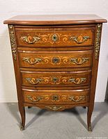 Front view of vintage Regency style wooden dresser with four drawers and brass hardware.