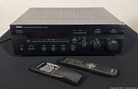 Front and top view of Yamaha RX-596 stereo receiver with two remotes placed in front.