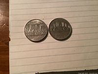 Obverse sides of two Canadian 1982 $1 coins showing commemorative and Voyageurs designs.