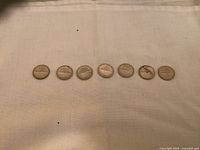 Seven Canadian dimes in a row showing the reverse sides with Centennial themed designs.