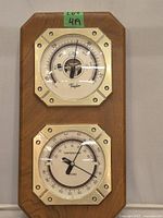 Front view of the wooden plaque with two octagonal dials. Upper dial is a barometer marked 'Taylor', lower dial shows temperature and humidity.