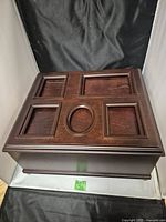 Closed view of the dark wooden picture box with decorative framed insets on lid.