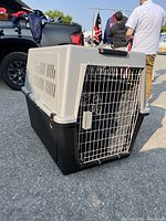Front-side view of the large Ferplast Atlas 70 pet carrier showing metal door, ventilation slots, and wheels for mobility.