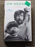 Front cover photo of hardcover book 'Jim Henson: The Biography' by Brian Jay Jones featuring black and white photo of Jim Henson with Muppets.