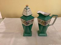 Photo of Noritake creamer and sugar shaker side by side showing front floral design