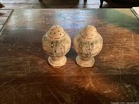 Front view of the pair of bulb-shaped salt and pepper shakers on wooden surface.