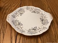 Top view of the cake plate showing the silver maple leaf motif and gold trim.