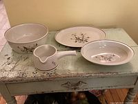 4-piece set of Royal Doulton Wild Cherry pattern including 9.5 inch round bowl, 10.25 inch oval bowl, 13.25 inch oval platter, and a double-spouted gravy boat on distressed table surface