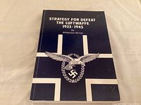 Paperback book titled 'Strategy For Defeat The Luftwaffe 1933-1945' by Williamson Murray lying flat on a beige fabric surface.
