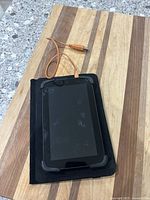 Amazon Fire tablet laying flat with orange USB cable and black case underneath.