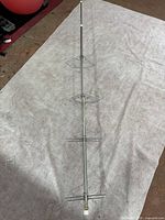 Full length photo of the chrome extendable pressure mount bathroom shelves showing all three corner wire shelves on a pressure rod.