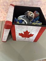 Open fabric folding storage box with Canadian maple leaf print, showing 5 assorted beach towels inside