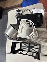 View of entire lot showing HP Deskjet 3000 printer, metal swing-lid garbage can, white plastic circular-hole plastic bag holder, and black rectangular plastic file holder on table.