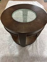 Top view of round wooden end table showing oval crackle glass insert and circular top with dark wood finish.