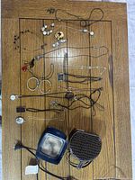 Various pieces of costume jewelry laid out on a wooden table with a blue ceramic Scentsy heater and brown faux crocodile skin jewelry travel case.