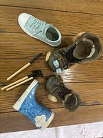 Photo showing all ceramic shoe planters and mini wooden garden tools scattered on a wooden floor.