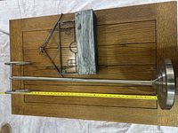 Photo of the tall chrome towel holder next to the farmhouse style planter/mailbox/newspaper holder, showing the dimensions of the towel holder with a measuring tape.