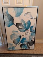 Front view of blue and grey floral print wall art in a black frame.