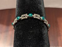 Front view of bracelet with green oval stones set in sterling silver and geometric link design.
