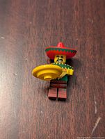 Front view of Lego minifigure Taco Tuesday Guy standing on wooden surface, showing sombrero, poncho detail, and yellow taco accessory.