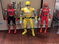 Photo of three action figures: Red, Yellow, and Crimson Ninja Storm Power Rangers standing upright on a shelf.