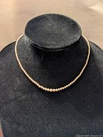 Front view of pearl choker necklace displayed on black velvet stand.