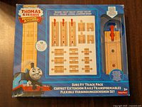 Front of box showing contents including 16 wooden train track pieces with illustrated track pieces and Thomas the Tank Engine image.