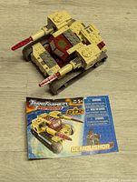 Constructed Transformers Armada Mega Bloks Demolisher in tank form placed on wood floor with front of instruction booklet showing.