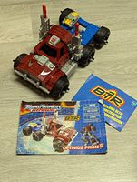 Front angled view of the assembled Optimus Prime figure in red, blue, silver, and black Mega Bloks with instruction manual and additional flyer placed beside it.