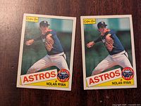 Front view of two Nolan Ryan 1985 O-Pee-Chee Astros baseball cards with identical images of Nolan Ryan pitching in a blue Astros uniform.