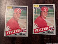 Front sides of two 1985 O-Pee-Chee Pete Rose baseball cards showing player in Cincinnati Reds red uniform with team logo and Reds name.