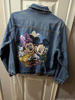 Back of the large denim jean jacket showing colorful Minnie Mouse and Mickey Mouse graphic.
