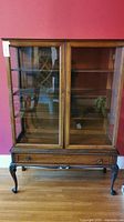 Front view of wooden china cabinet showing double glass doors and lower drawer