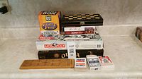 Stack of board games including Family Feud cards, Monopoly, Mt. Rushmore puzzle, Ouija board, cribbage board, magnetic chess/checkers, and decks of playing cards laid out on table.