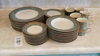 Full 10-place setting china set of plates, bowls, cups, and saucers arranged on countertop.