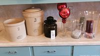 Overview of all items: two pottery canisters, black glass canister, two red votives, two clear hurricane shades.