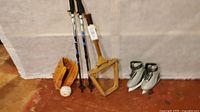Photo of the full lot including the baseball glove, baseball, walking poles, vintage tennis racquet, ice skates, all arranged on the floor in front of a white backdrop.