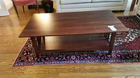 Coffee table full view on rug showing rectangular top and lower shelf