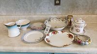 Various china including platters, bowls, gravy pitcher, creamers, and serving dishes arranged on a countertop
