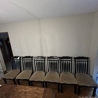 Full front view of six Ashley Furniture dining chairs in a row against wall, showing seat color and carved wood backs.