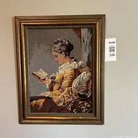 Full view of the framed needlepoint tapestry hanging on the wall, showing the entire piece and frame.